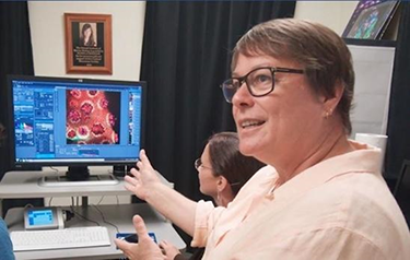 Dr. Ruth Gates showing a screen with a coral microscopy image.